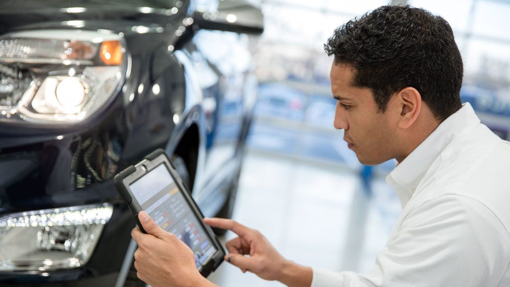 Chevrolet service technician holding a tablet and reviewing a spring maintenance checklist during a service appointment at Laria Chevrolet Buick in Rittman, OH.